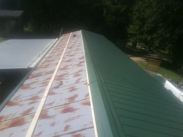 Old rusted panels beside newly installed green metal roofing — Wind Damage Roof Repair by Roofing Brothers in Sheldahl