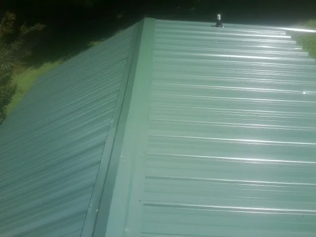 New green metal panels meeting at the ridge of a roof — Flat Roof Repair work by our crew in Sheldahl
