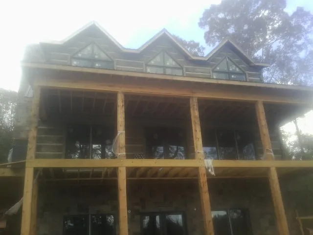Dormers and porch framing on a large log home under construction — Roof Coating work by our crew in Sheldahl