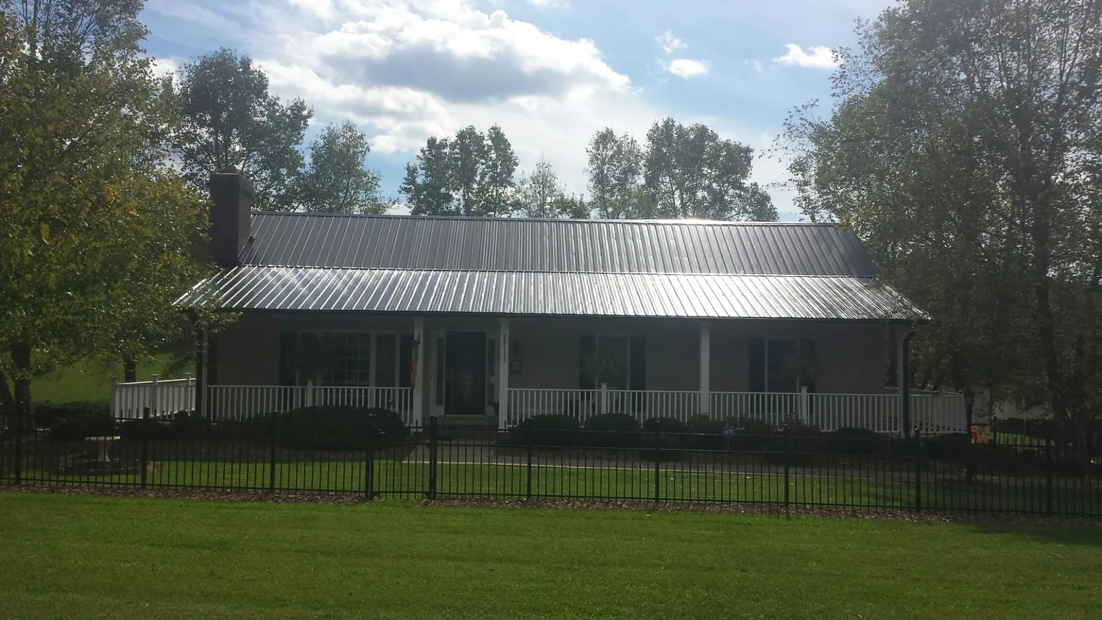 Gray metal roof on a brick ranch with a full width front porch — Gutter Guard Installation work by our crew in Sheldahl