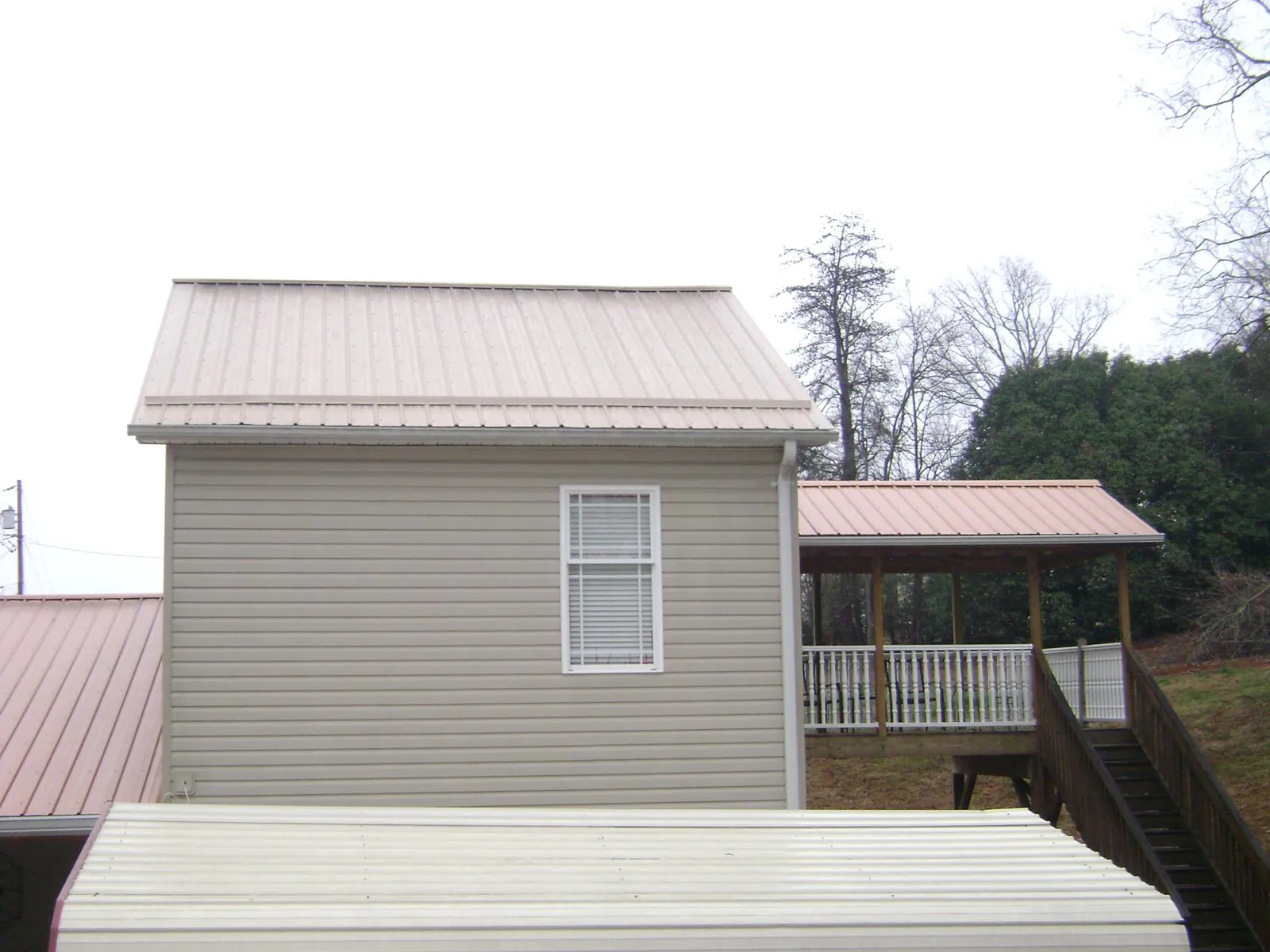 Tan metal roofs on a two story addition and attached porch, from a Roof Replacement job in Sheldahl